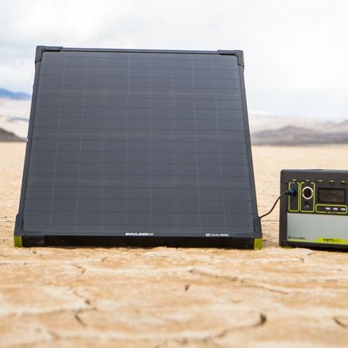 A Goal Zero Boulder 50 Solar Panel feeding power to a Yeti power station in a dessert landscape with moutains in the background.