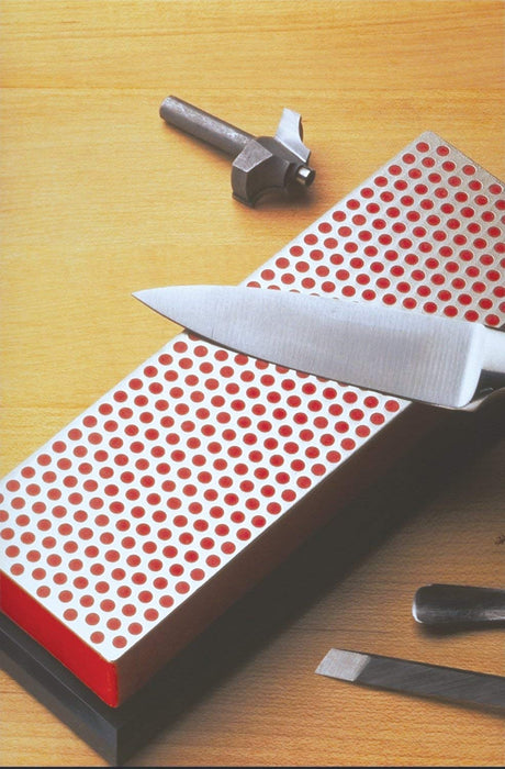 A knife being sharpened across the DMT Diamond Course Grit Sharpener. The dot pattern is of a red colouring on a black base.