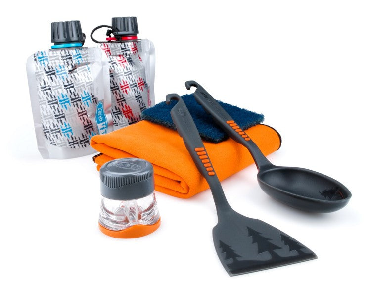 GSI Outdoors Kitchen Essentials pack with a spatula, cooking ladle, salt & pepper shakers, cleaning rag, drying towel, and two swappable condiment pouches. The ladle and spatula have the outdoor logo of 3 trees. 