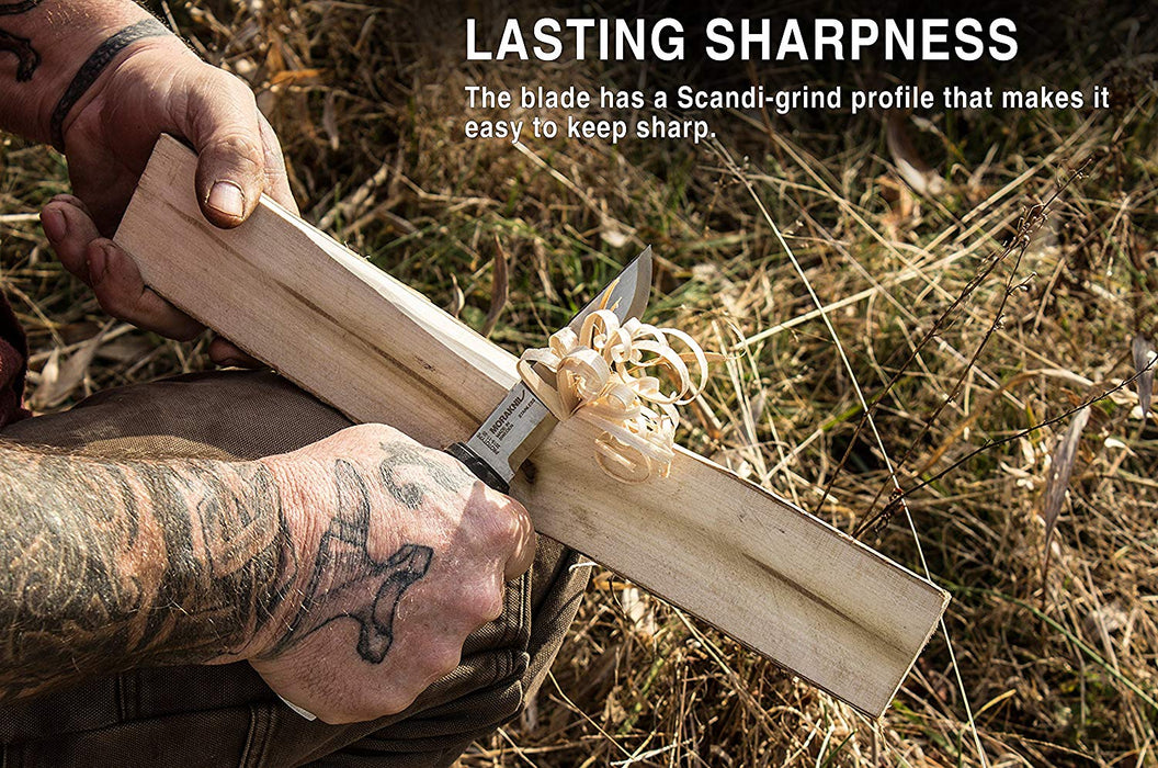 A man with a full sleeve tattoo is shaving wood off a piece of firewood using a Morakniv Full tag fixed blade knife. 