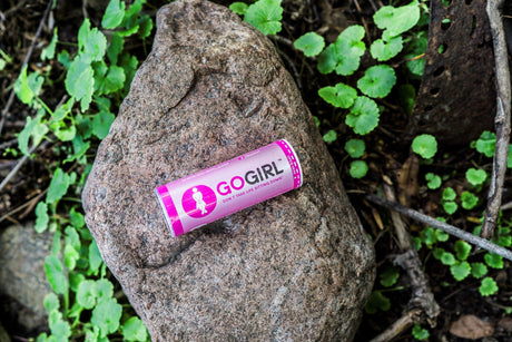 Go Girl Placed on a rock in the woods, surrounded by greenery.