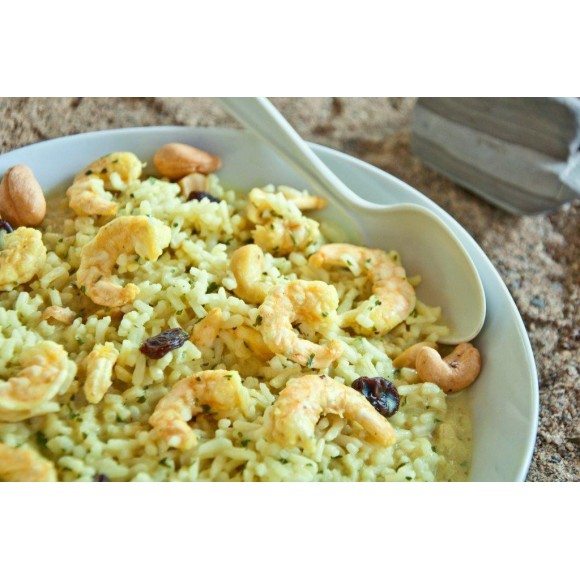 A white bowl of the preppared Happy Yak Shrimp Curry with Rice Freeze Dried Food with a white spoon on a stone like surface.