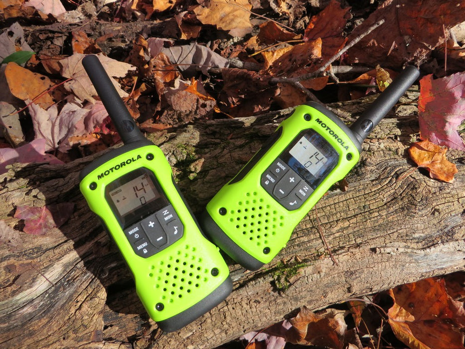 Two lime green and black Talkabout T600 Radios on a tree log in the fall. Leaves populate the surrounding area.