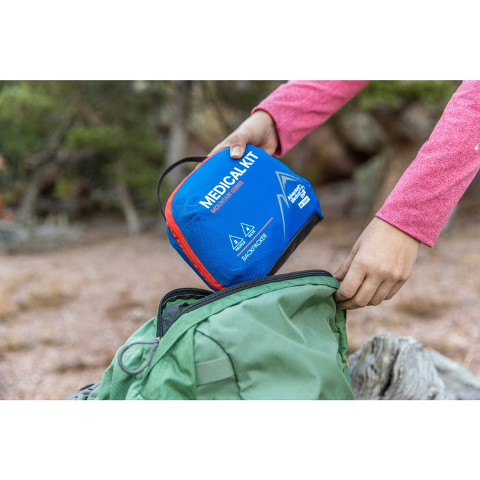 Women putting away Adventure Backpacker Medical Kits in her backpack